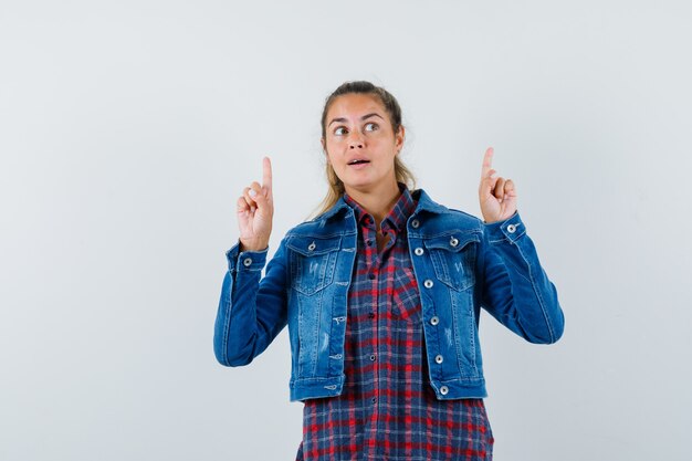 Woman in shirt, jacket pointing up and looking hopeful , front view.