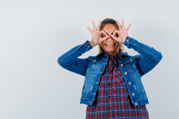 Free photo woman in shirt, jacket showing glasses gesture and looking happy , front view.