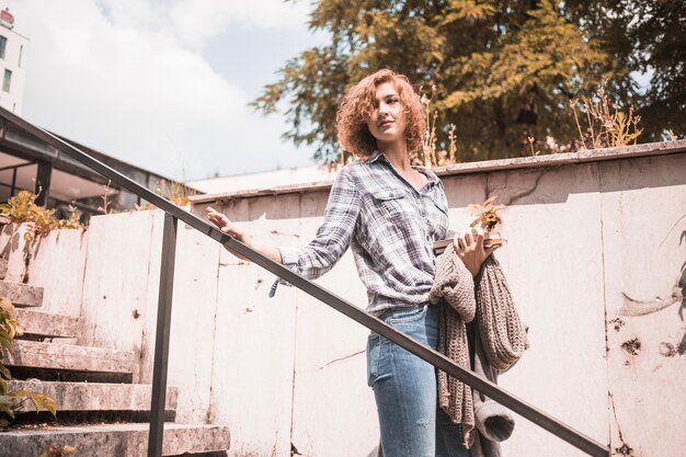 Woman in shirt and jeans going down on steps