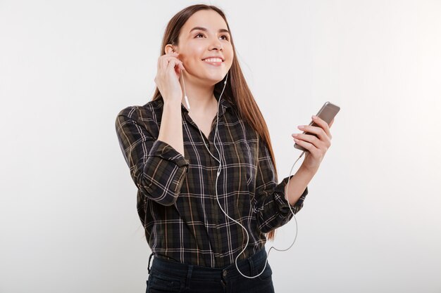 電話で音楽を聴くシャツの女性