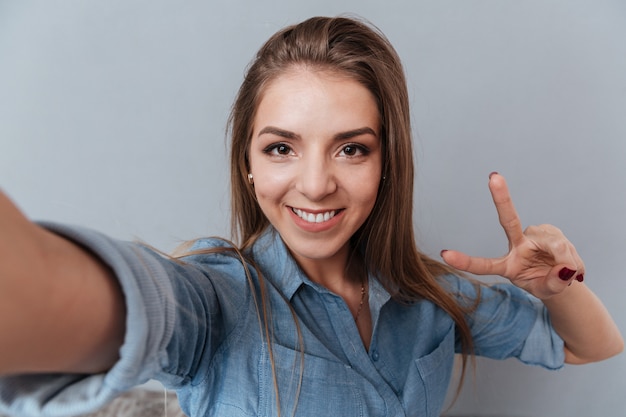 Foto gratuita donna in camicia che fa selfie in studio