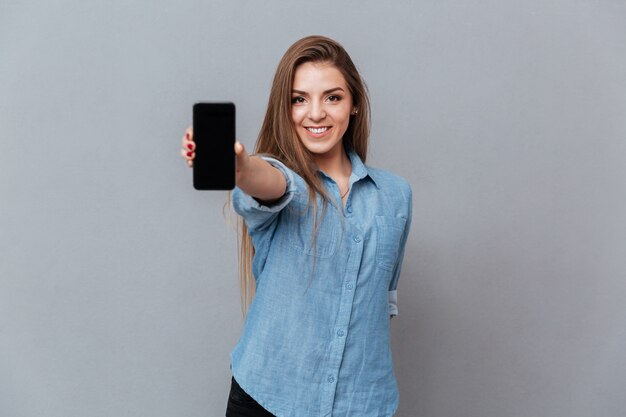 Woman in shirt showing blank smartphone screen