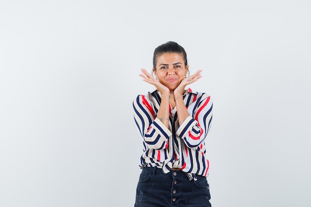 woman in shirt, skirt holding hands under chin and looking cute