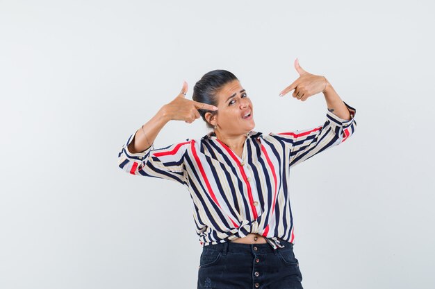 woman in shirt, skirt pointing at herself and looking confident