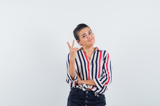 woman in shirt, skirt showing victory gesture and looking confident