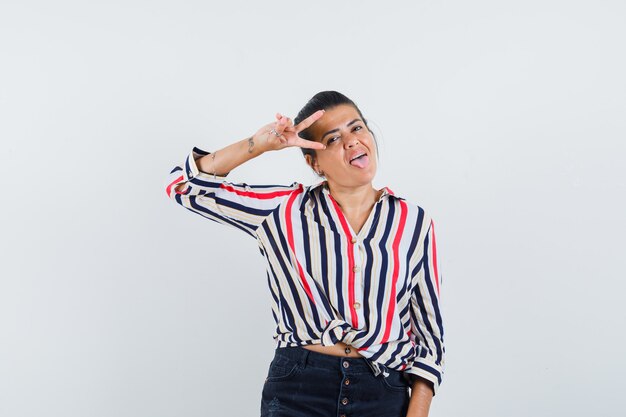 woman in shirt, skirt showing victory gesture and looking crazy