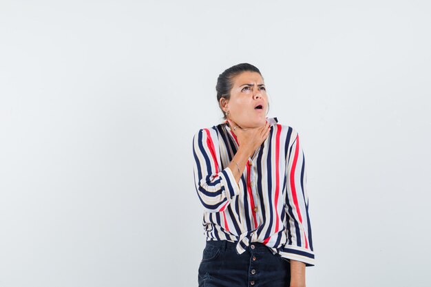 woman in shirt, skirt suffering from sore throat and looking sick