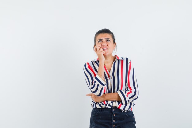 woman in shirt, skirt thinking while looking up and looking anxious