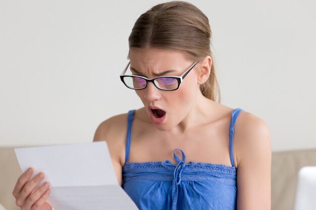 Free photo woman shocked when reading letter with bad news