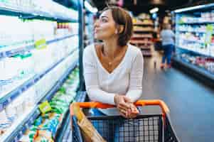 Free photo woman shopping at the grocery store, by the refrigerator