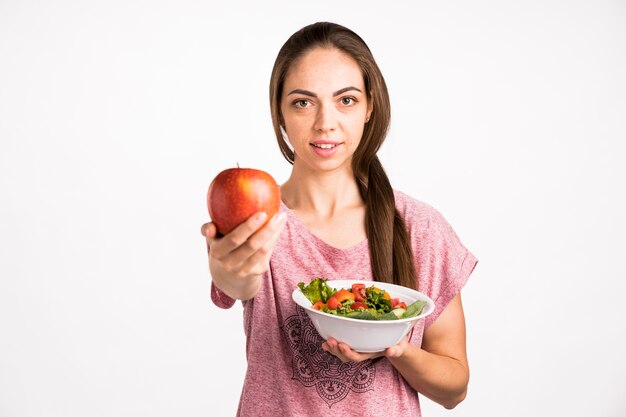 Woman showing an apple and looking at camera