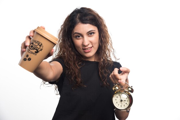 白い背景の上の時計とコーヒーのカップを示す女性。高品質の写真