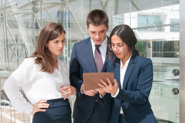 Woman showing data on tablet, colleagues looking concentrated