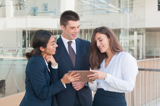 Woman showing data on tablet, colleagues looking involved