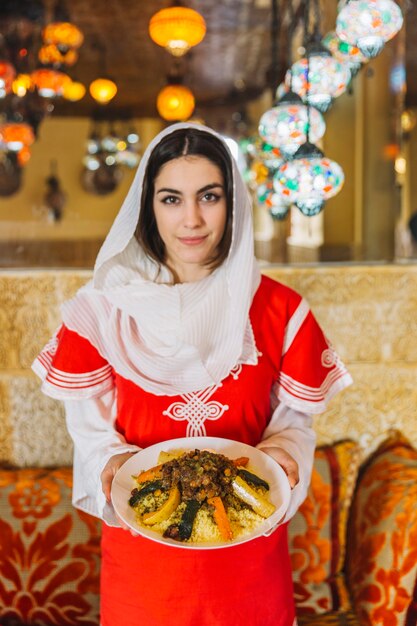 Женщина показывает блюдо из арабской пищи