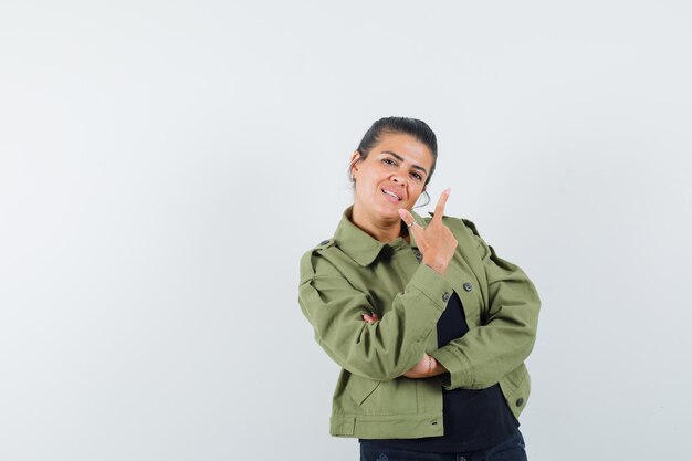 woman showing gun gesture in jacket, t-shirt and looking confident.