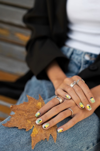 Foto gratuita donna che mostra la sua nail art sulle unghie con foglia d'autunno