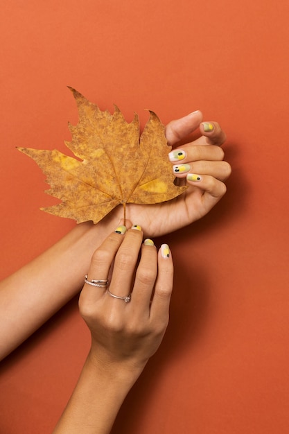 秋の葉と指の爪に彼女のネイルアートを示す女性