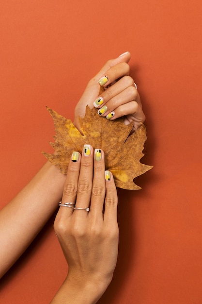 Free photo woman showing her nail art on fingernails with autumn leaf