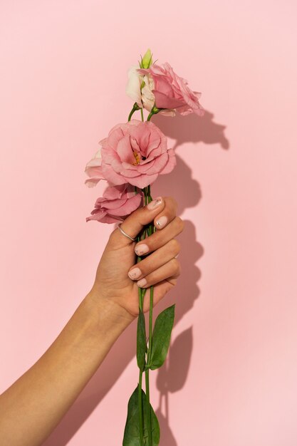 Женщина показывает свой маникюр на ногтях с цветком