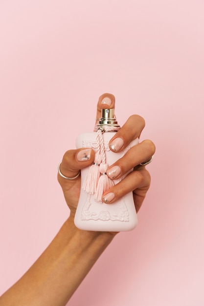 無料写真 香水で指の爪に彼女のネイルアートを示す女性