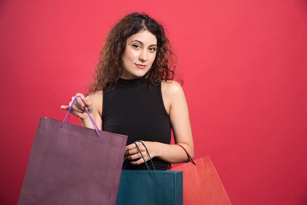 Woman showing her new buying clothes on red background. High quality photo