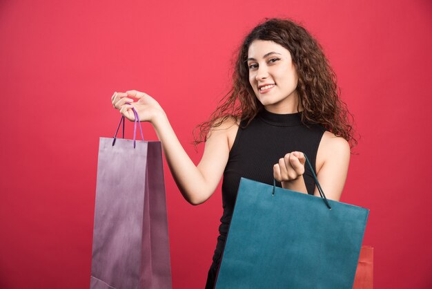 赤い背景に彼女の新しい購入服を示す女性。高品質の写真