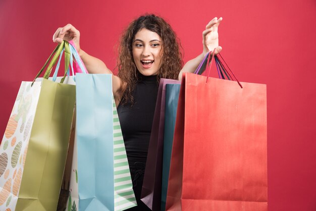 Woman showing her new buying clothes on red background. High quality photo