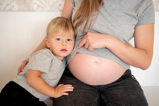 그녀의 아들 옆에 그녀의 임신 배꼽을 보여주는 여자