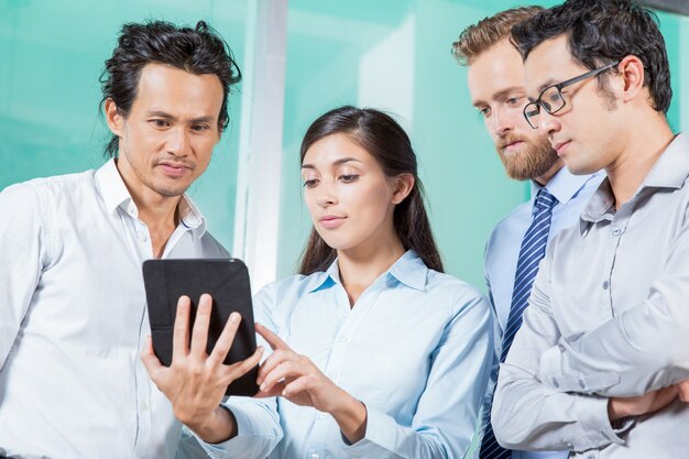 Woman Showing Information on Tablet to Colleagues