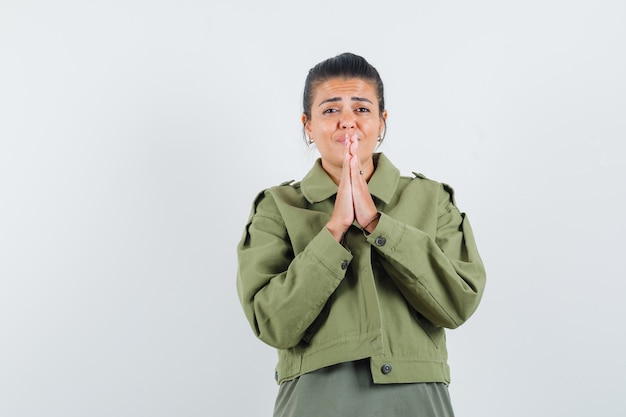 Free photo woman showing namaste gesture in jacket, t-shirt and looking dreamy