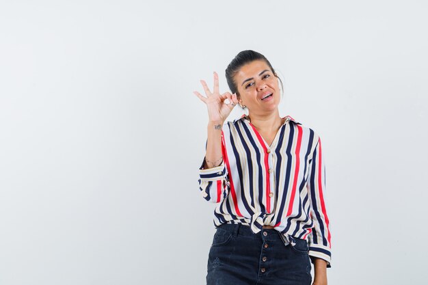 woman showing ok gesture in shirt, skirt and looking confident