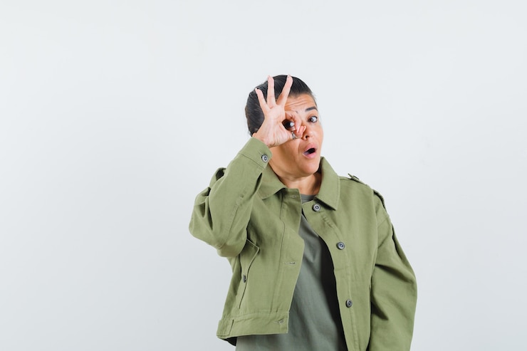 Free Photo woman showing ok sign on eye in jacket, t-shirt and looking amazed