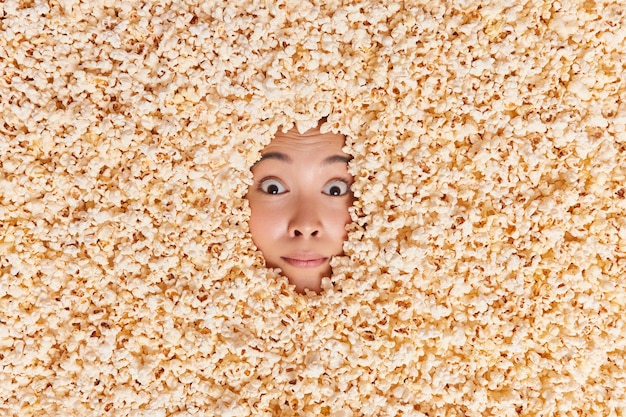 woman showing only face covered with delicious sweet popped corn