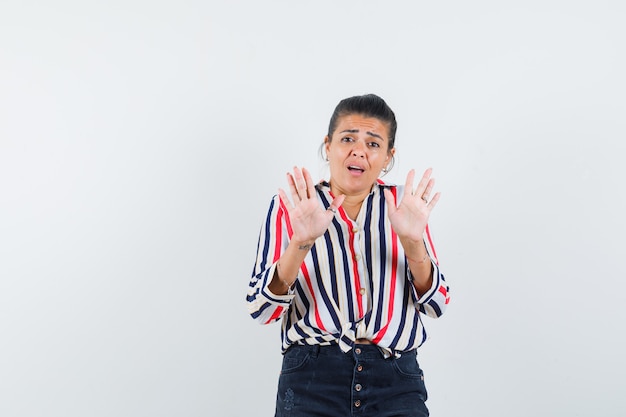 woman showing refusal gesture in shirt, skirt and looking scared