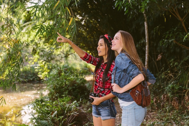 Foto gratuita donna che mostra qualcosa alla sua amica nella foresta