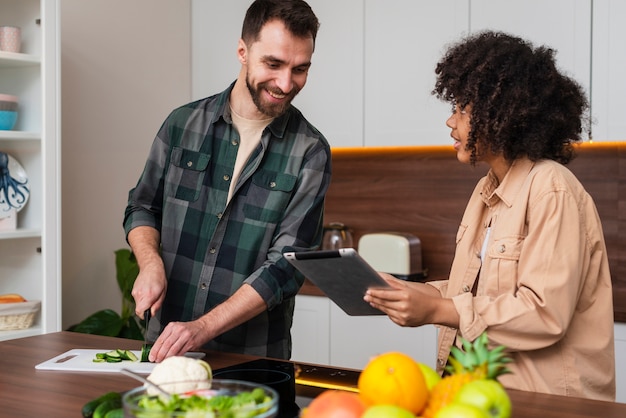 料理の男性にタブレットで何かを見せて女性