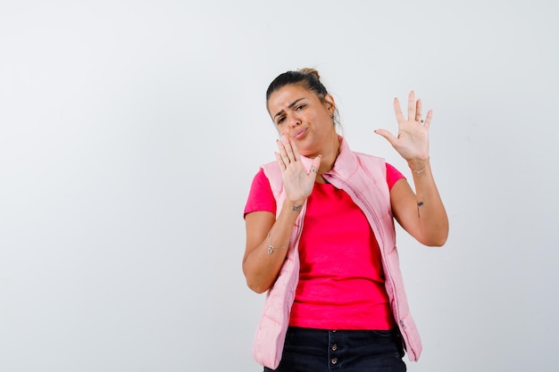 Woman showing stop gesture in t-shirt, vest and looking annoyed