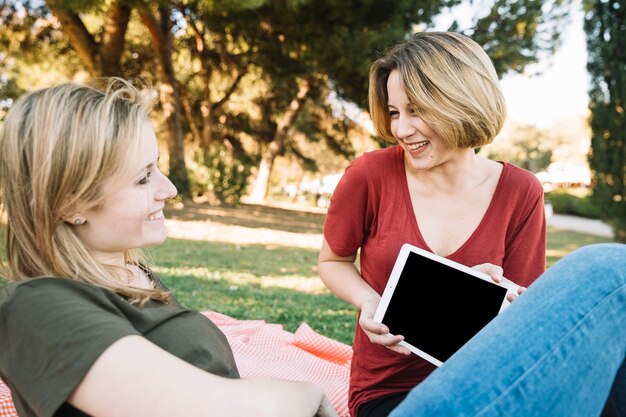 Woman showing tablet to friend