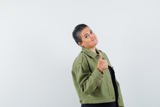 woman showing thumb up in jacket, t-shirt and looking confident.