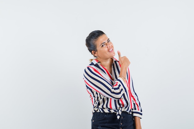 woman showing thumb up in shirt, skirt and looking satisfied.