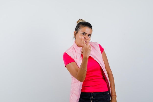 Woman showing victory gesture in t-shirt, vest and looking confident 