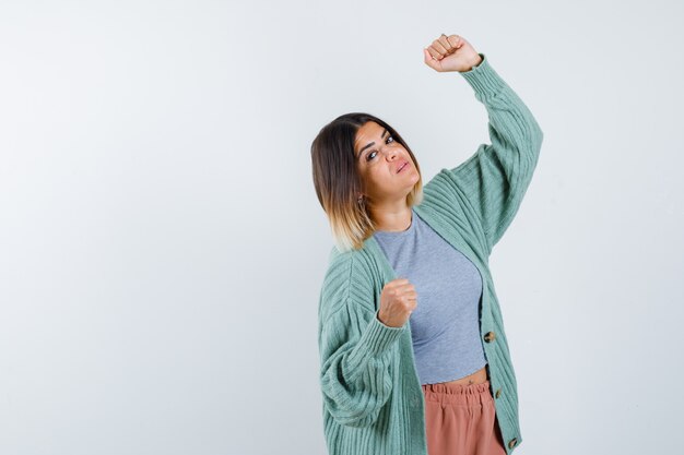 Woman showing winner gesture in casual clothes and looking lucky. front view.