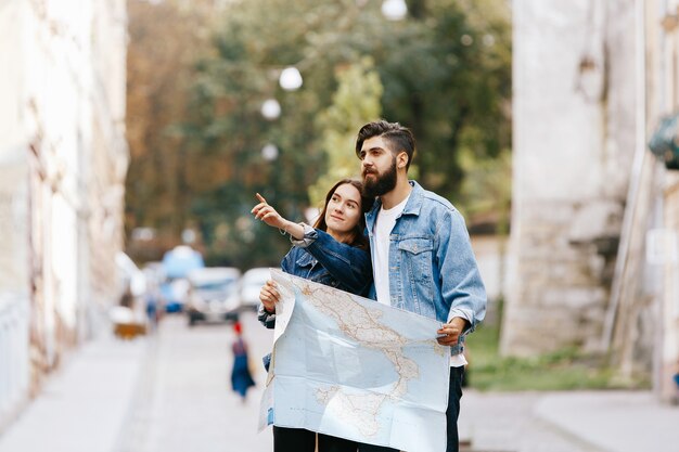 Женщина показывает что-то своему бородатому мужчине, стоящему вместе с туристической картой