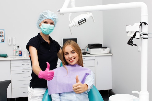 Woman shows thumb up sitting with a stomatologist at dentist office