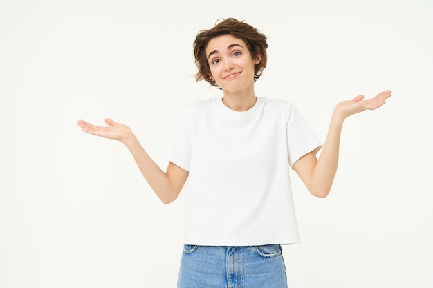 Free photo woman shrugs her shoulders looks clueless doesnt know anything stands confused against white