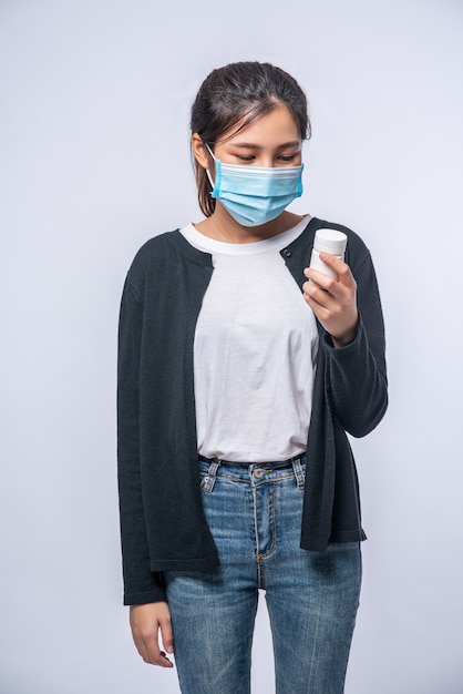 A woman sick standing with a bottle of medicine