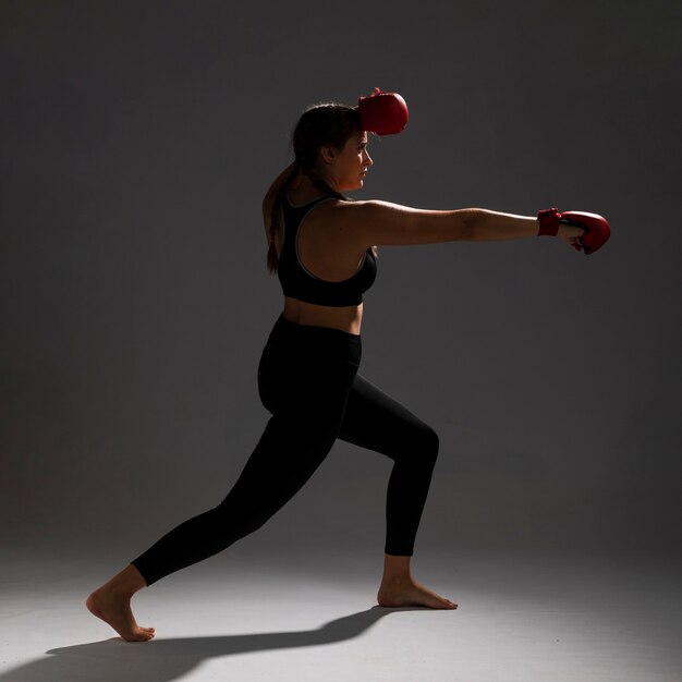 Женщина сбивает кулаком боксерские перчатки
