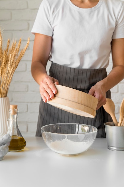 Free photo woman sifting flour over bowl