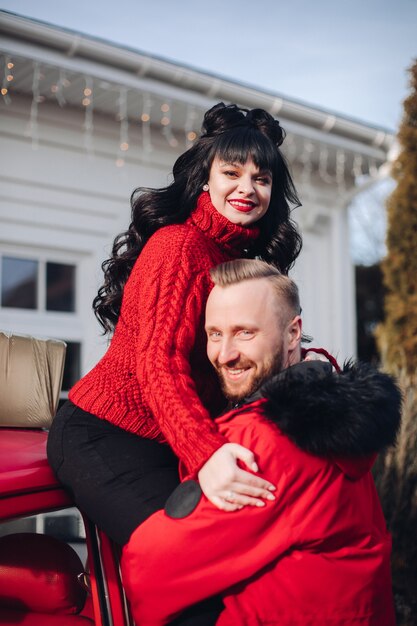 A woman sits in her husband's arms and smiles near the home